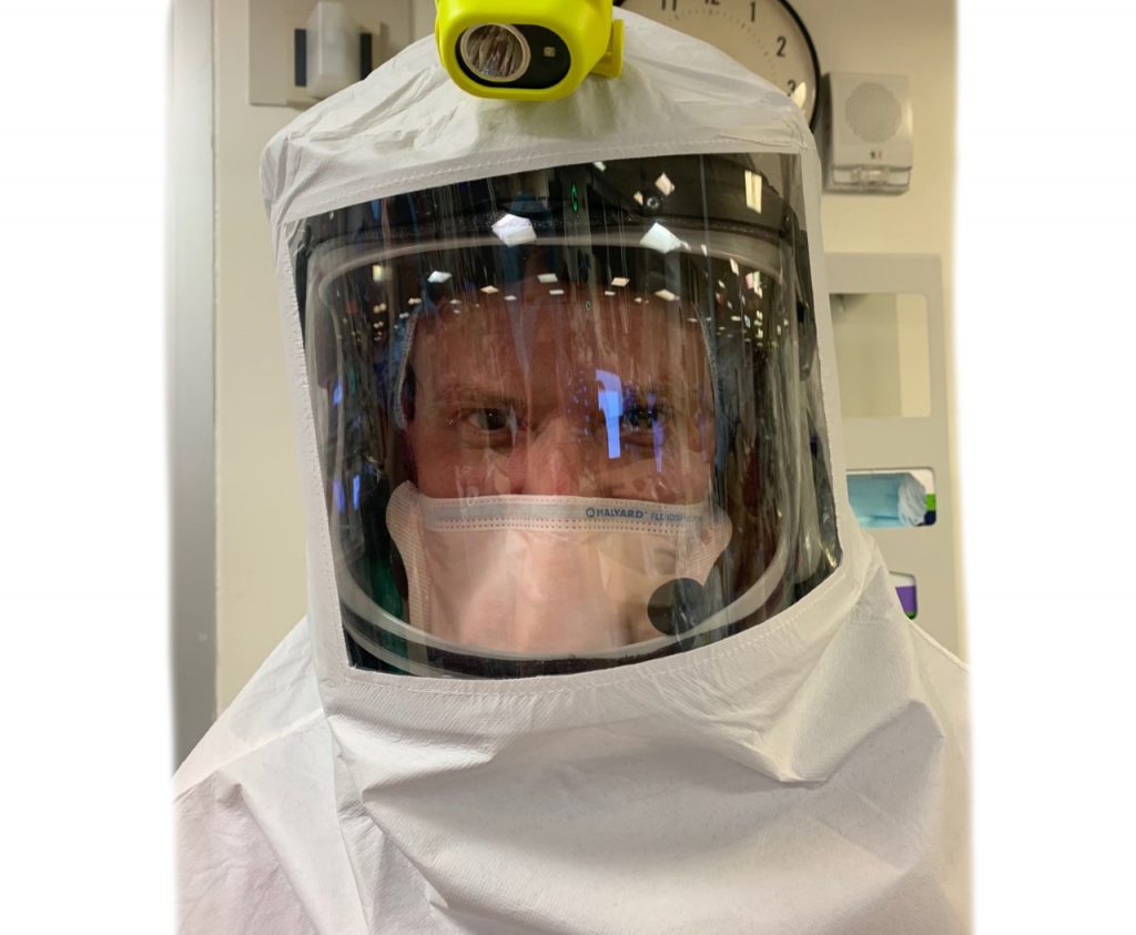 Medical personnel wearing protective hoods and suits.